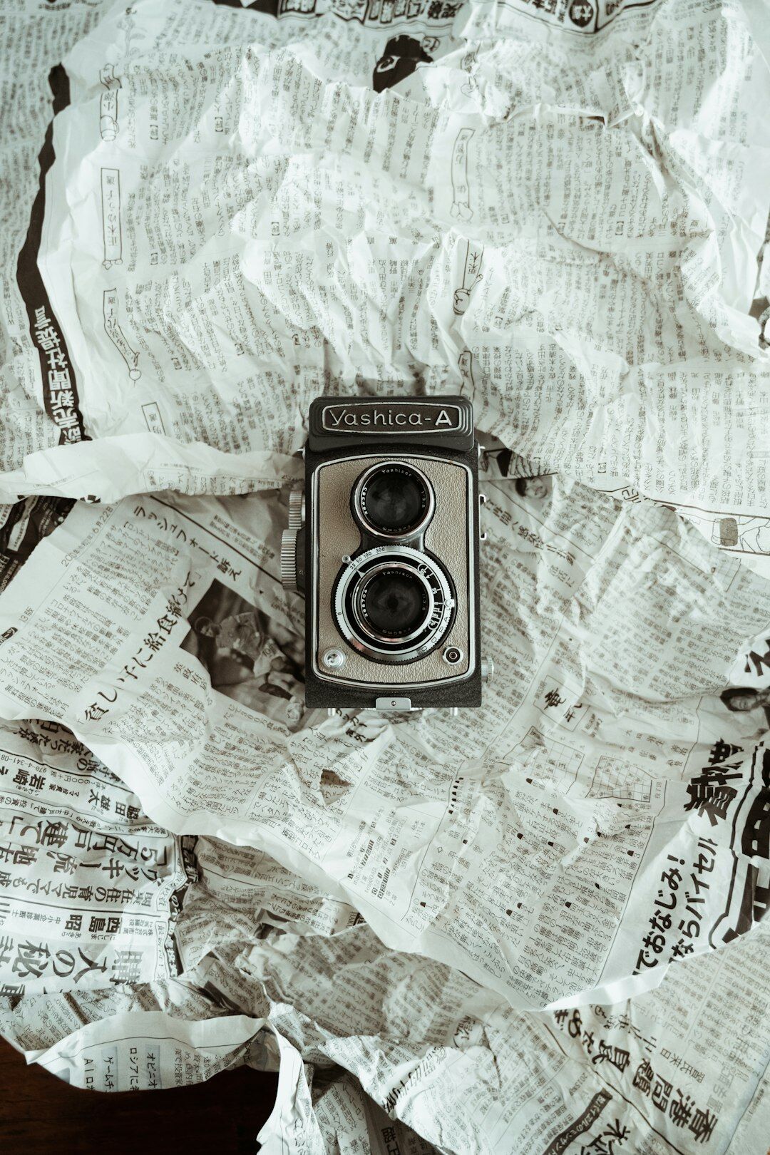 Vintage film camera resting on a stack of old photographs